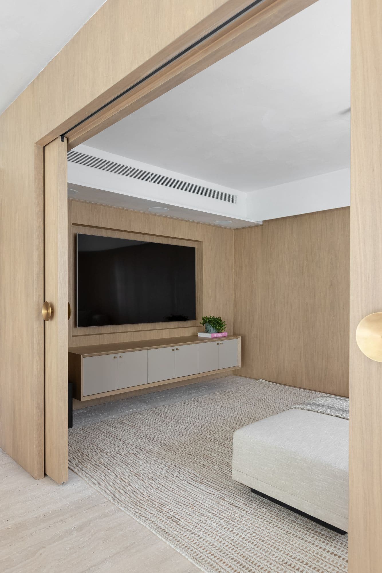 Porta de correr em lâmina de madeira natural aberta para a sala de TV